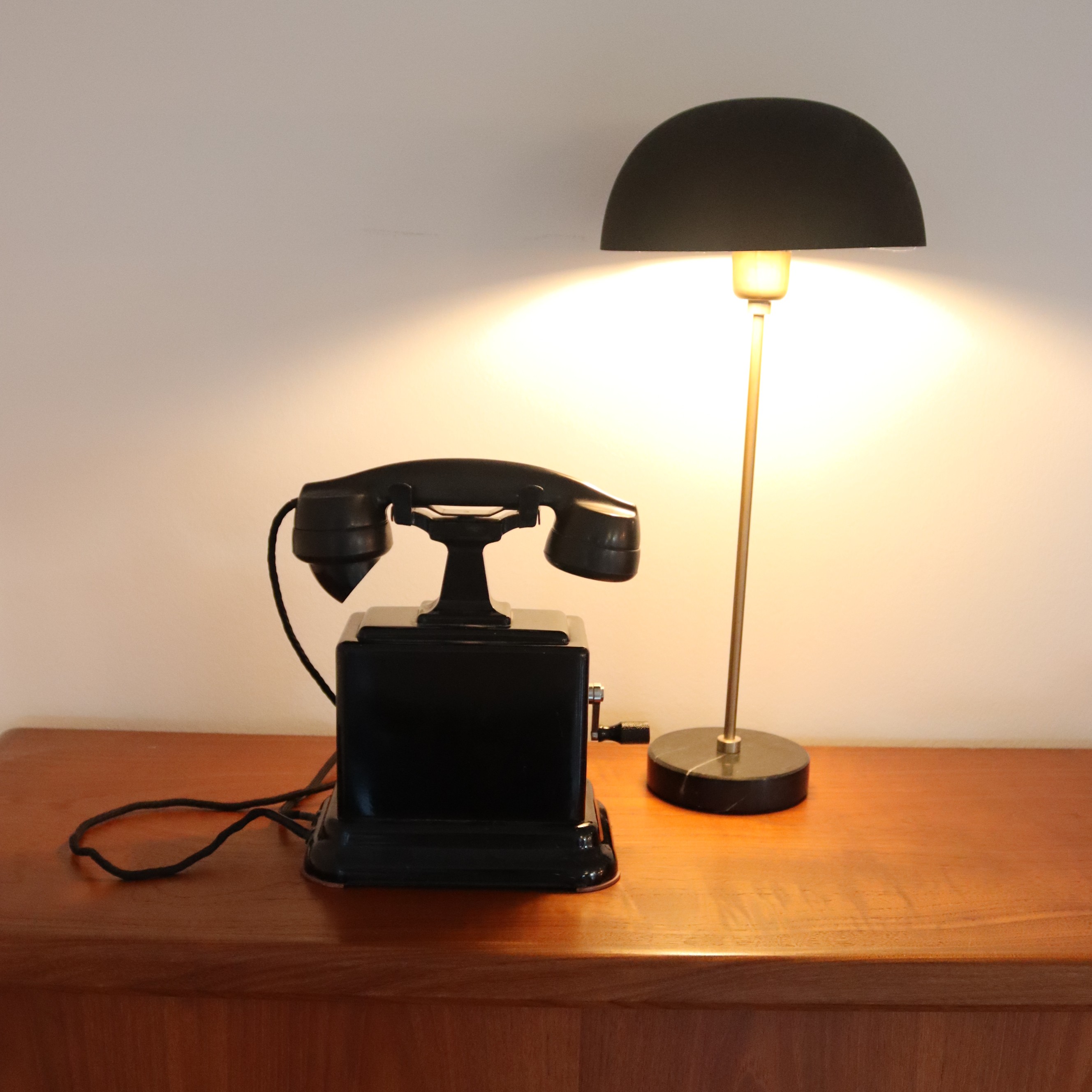An antique telephone beside a lit table lamp