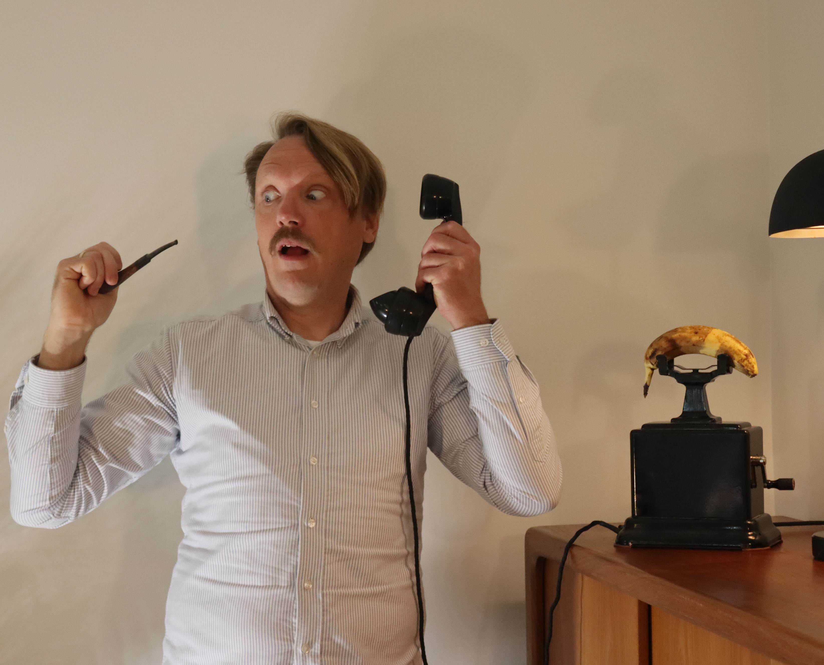 Nicolaj holding a pipe and telephone receiver beside a banana on the telephone